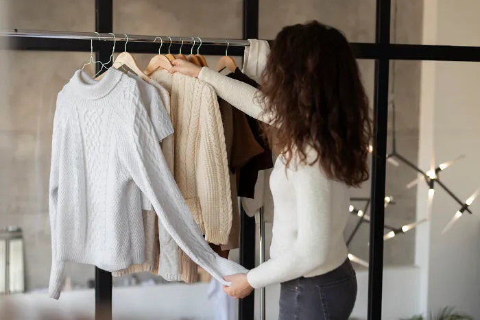 Woman with long hair holding a sweater from a clothing rack, symbolizing the final straw in a former friendship.