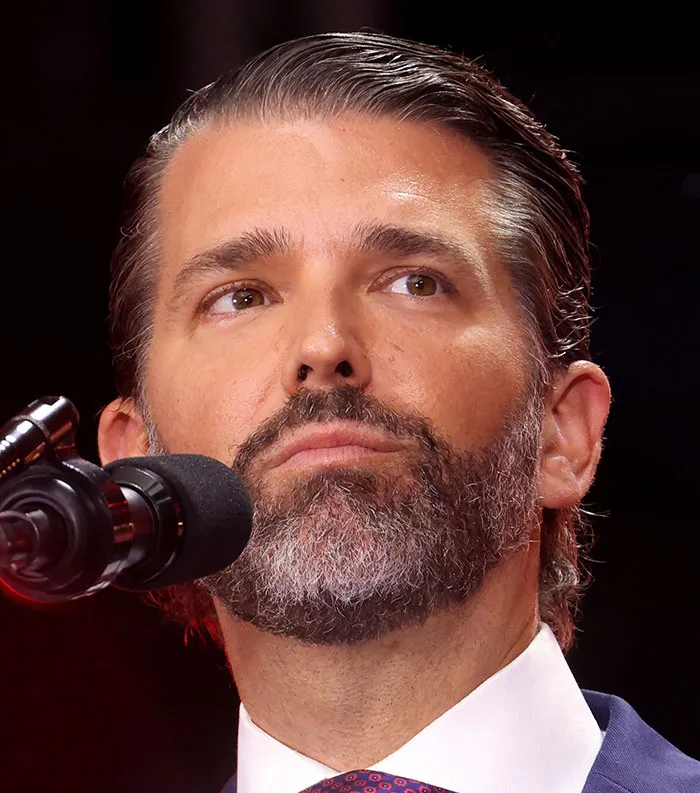 Close-up of a man speaking at a microphone with a serious expression, representing most disliked celebrities 2025.