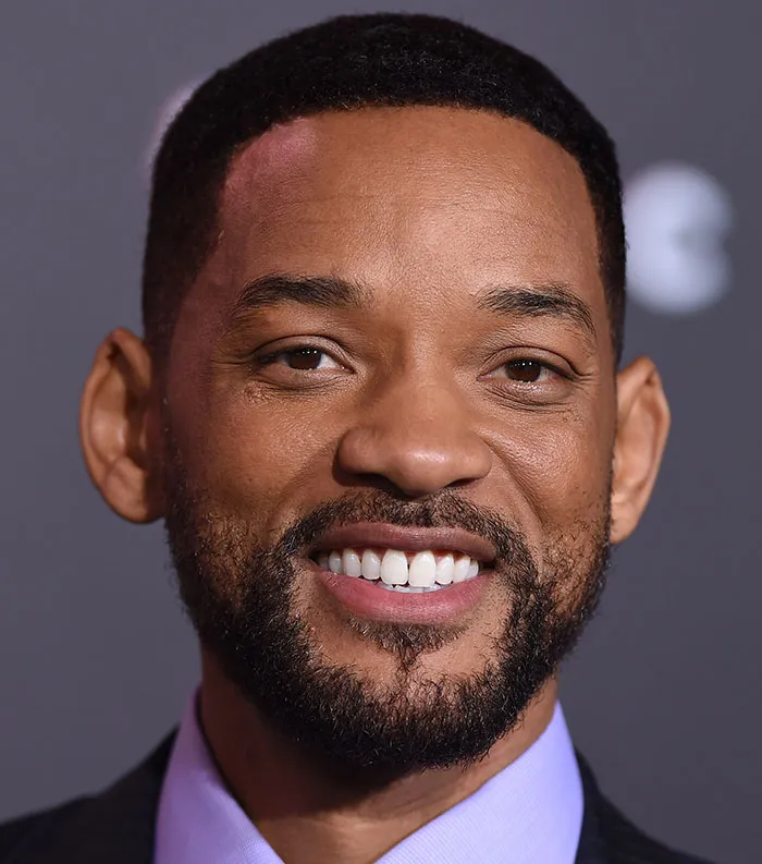Close-up of a smiling male celebrity at an event, representing one of the most disliked celebrities of 2025.