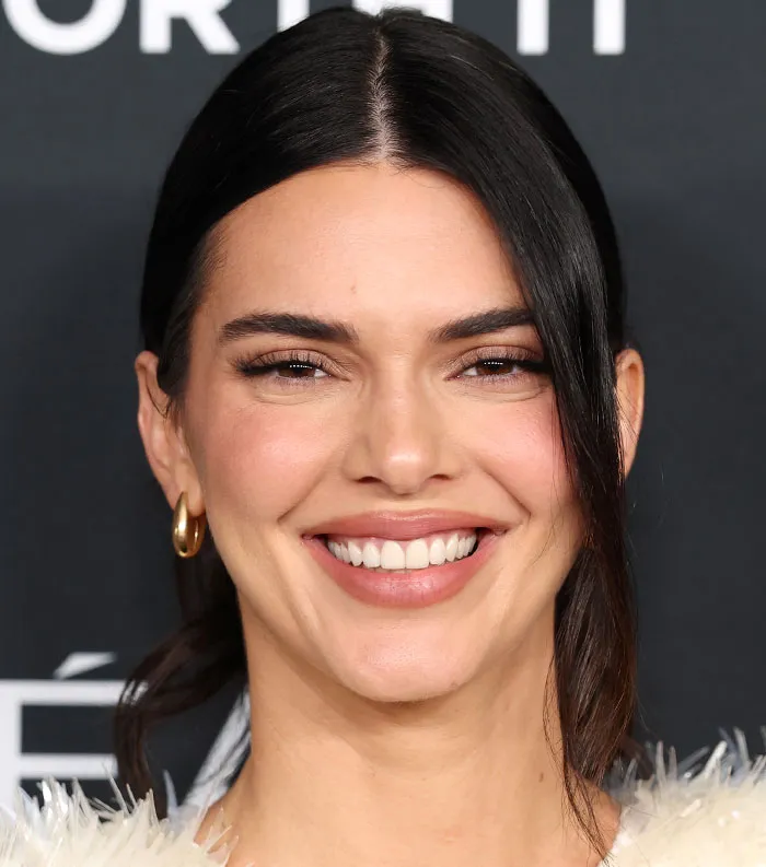 Close-up of a smiling woman with dark hair, gold hoop earrings, and makeup, representing most disliked celebrities of 2025.