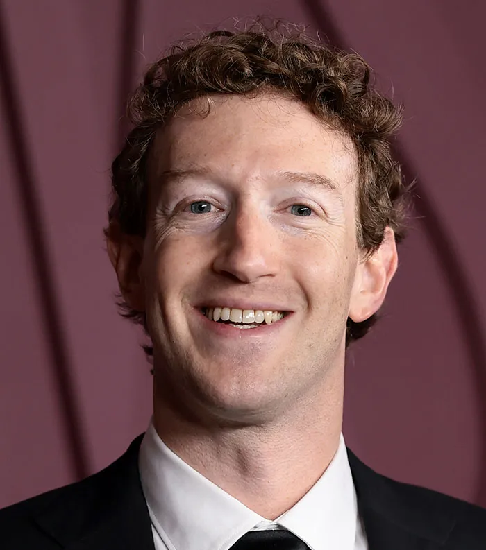 Close-up of a smiling man in a black suit and tie, representing the most disliked celebrities of 2025.