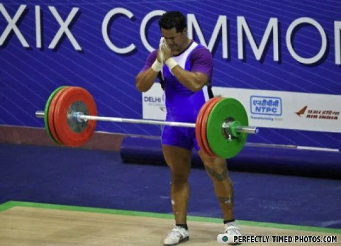 Weightlifter standing with hands pressed together in front of barbell in a perfectly timed photo competition setting.