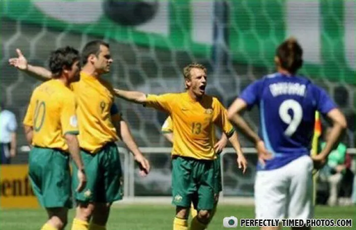 Soccer players reacting intensely on the field in a perfectly timed photo capturing a dramatic moment during the match.