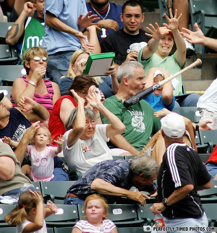 Crowd at baseball game reacts as bat flies toward man’s face in a perfectly timed photo capturing an impressive moment.