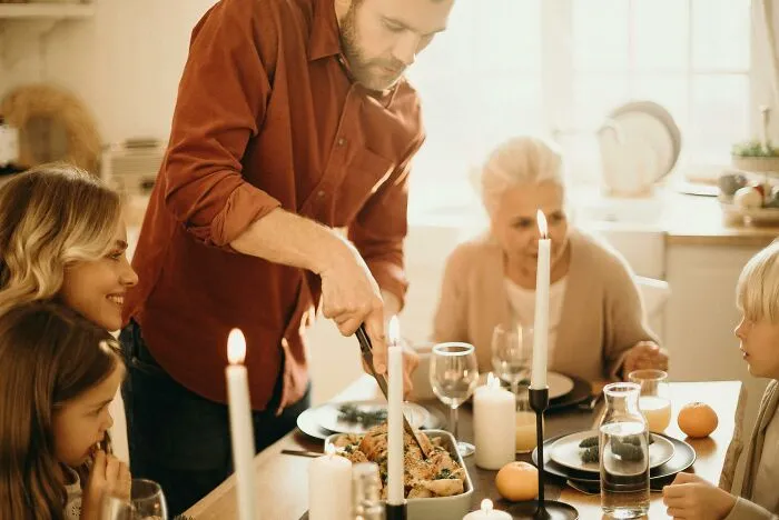 Family gathered around a candlelit table having dinner, illustrating reactions to horrible Christmas gifts.