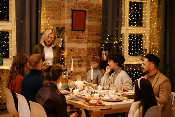 Family gathered around a festive Christmas dinner table with warm lights, reflecting on disappointing holiday gifts.
