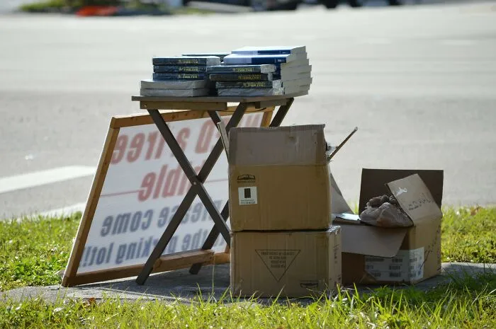Stack of books and cardboard boxes on a roadside table representing people’s dislike for horrible Christmas gifts.