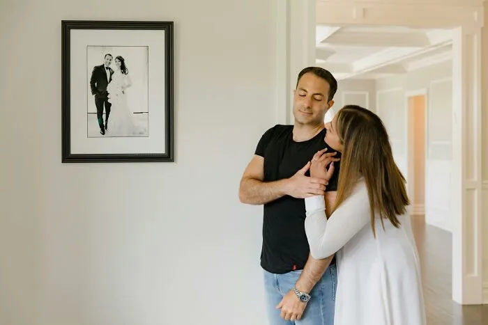 Couple posing near a framed photo in a home, illustrating reaction to horrible gifts during Christmas gift exchange.