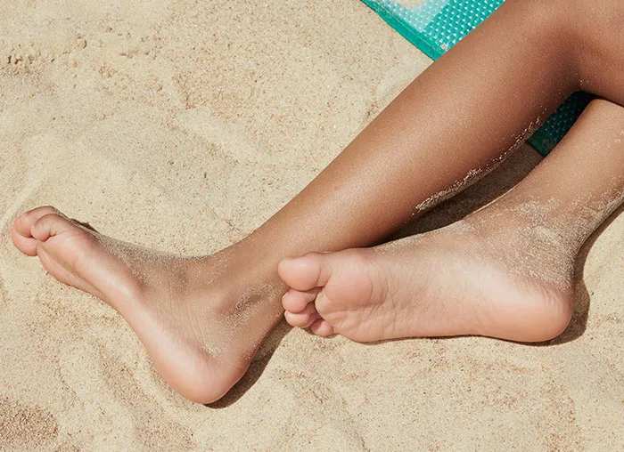 Bare feet resting on sandy beach, showing skin texture and sand grains, illustrating the mammalian dive reflex concept.