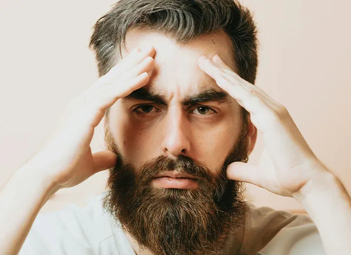 Man with beard concentrating and holding temples, illustrating focus on the mammalian dive reflex in the human body.