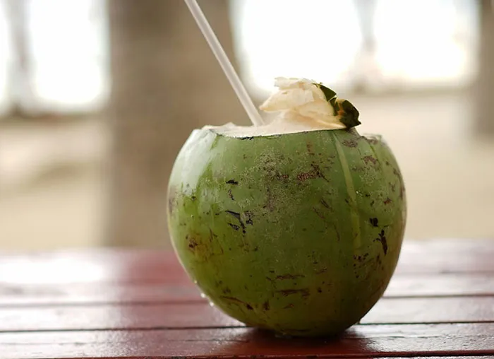 Green coconut with a straw on a wooden table, illustrating a natural source related to the mammalian dive reflex.