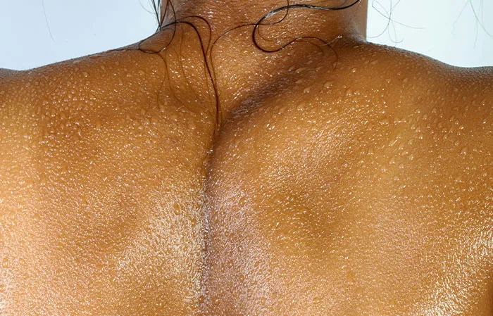 Close-up of a wet human back showing skin texture and water droplets, illustrating the mammalian dive reflex in the human body.