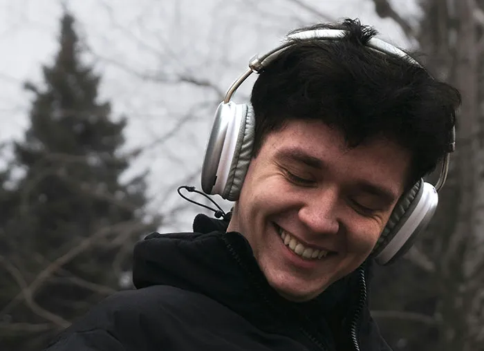 Young man smiling outdoors with headphones, illustrating concepts related to the mammalian dive reflex in the human body.