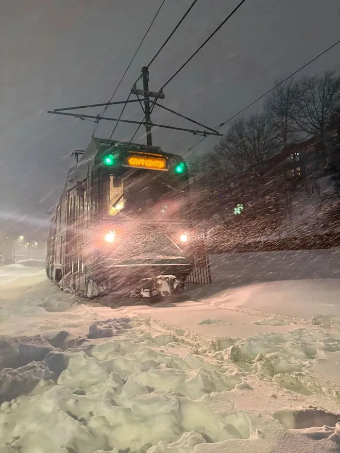 Snowstorm hitting U.S. streetcar with heavy snow and strong winds during nighttime winter storm conditions.