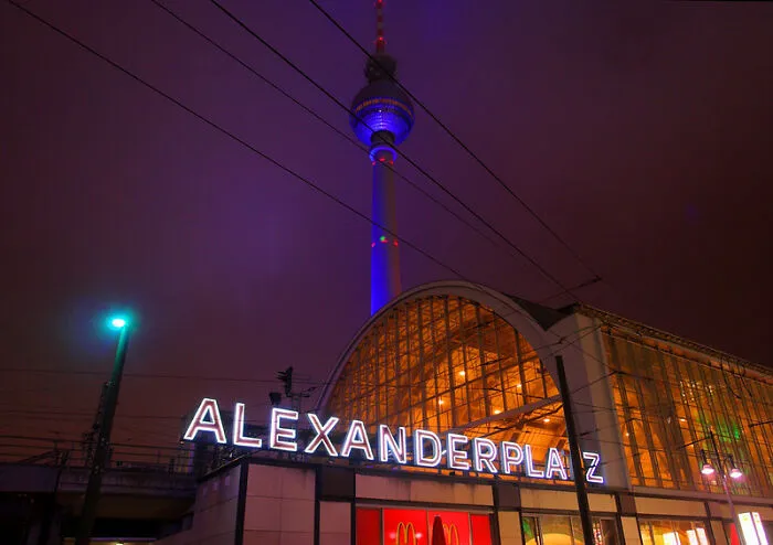 Alexanderplatz at night with illuminated signage and TV tower, a disappointing tourist attraction many locals still don’t get.