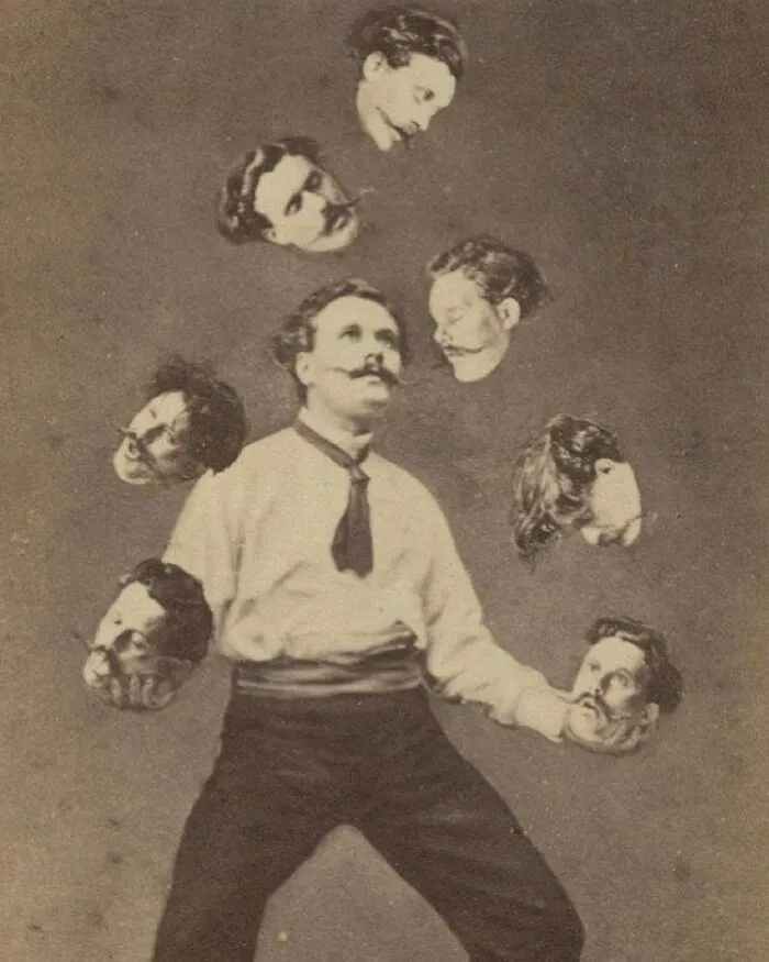 Man juggling seven floating heads in an old black and white photo with a strange and creepy vintage vibe.