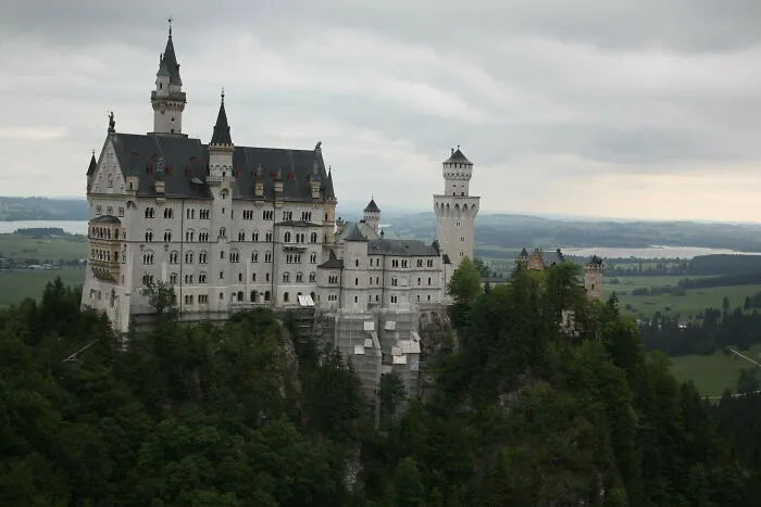 Neuschwanstein Castle perched on a hilltop surrounded by greenery, representing disappointing tourist attractions locals overlook.