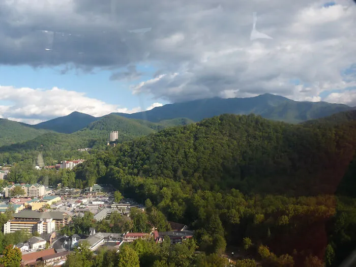 A small tourist town surrounded by lush green hills and mountains under a partly cloudy sky.
