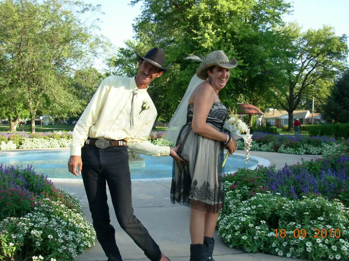 Man in cowboy hat playfully pulling bride's dress outdoors, creating one of the awkward wedding photos with humor.