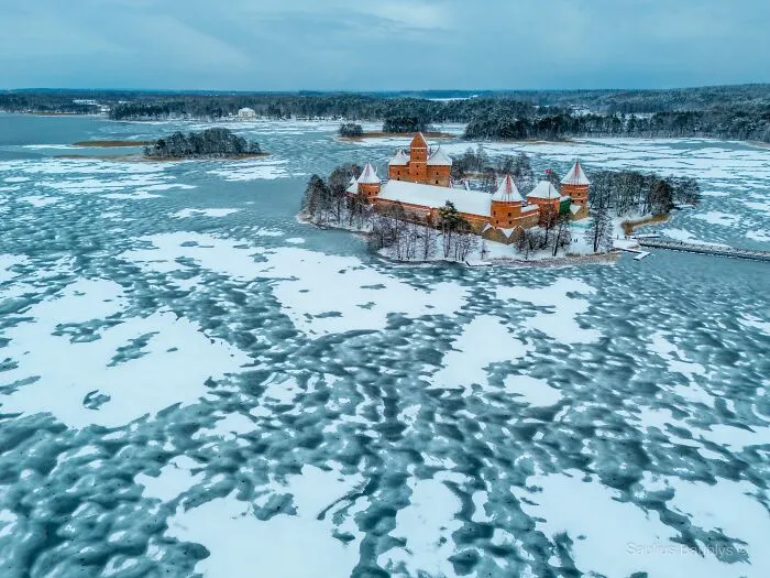 Aerial view of a snowy castle surrounded by icy water and winter landscape for cozy winter images.