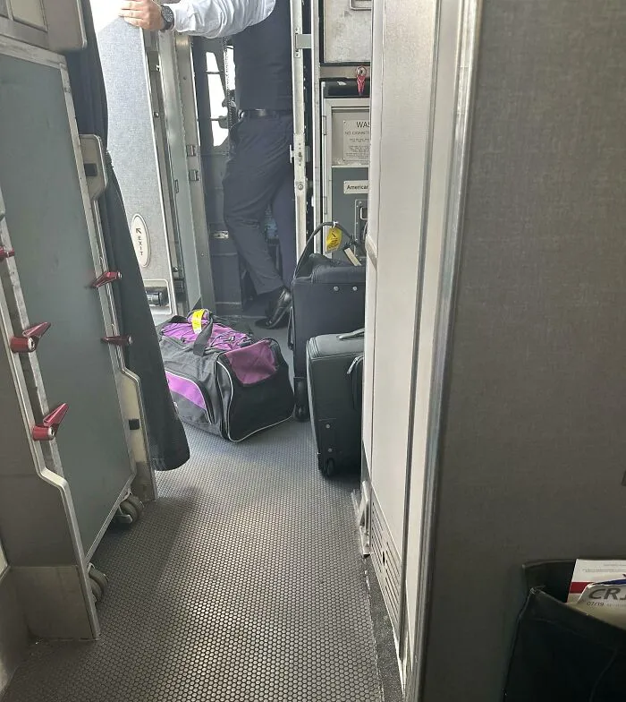 Persona bloqueando la entrada del avión con equipaje, mostrando un caso de ser grosero y ser avergonzado en línea.
