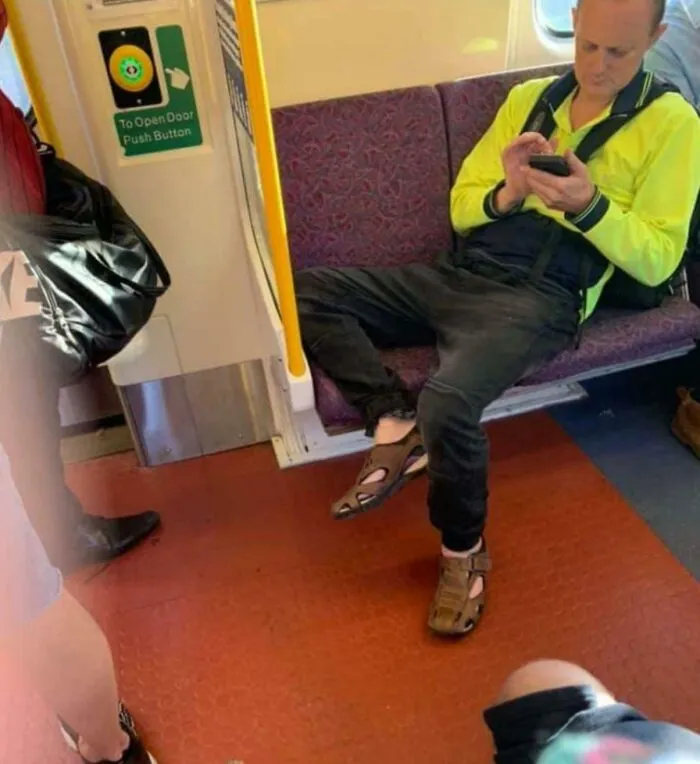 Hombre sentado en transporte público con piernas abiertas, siendo un jerk y causando incomodidad a otros pasajeros.