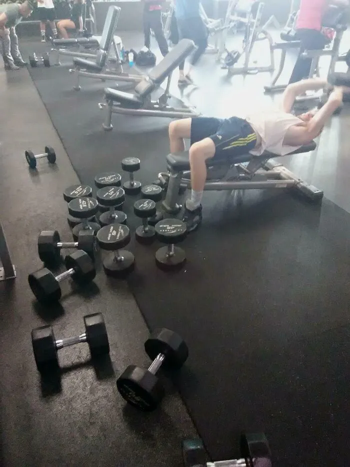 Persona siendo tan grosera en gimnasio bloqueando espacio con pesas y causando molestia a otros usuarios en el área de entrenamiento.