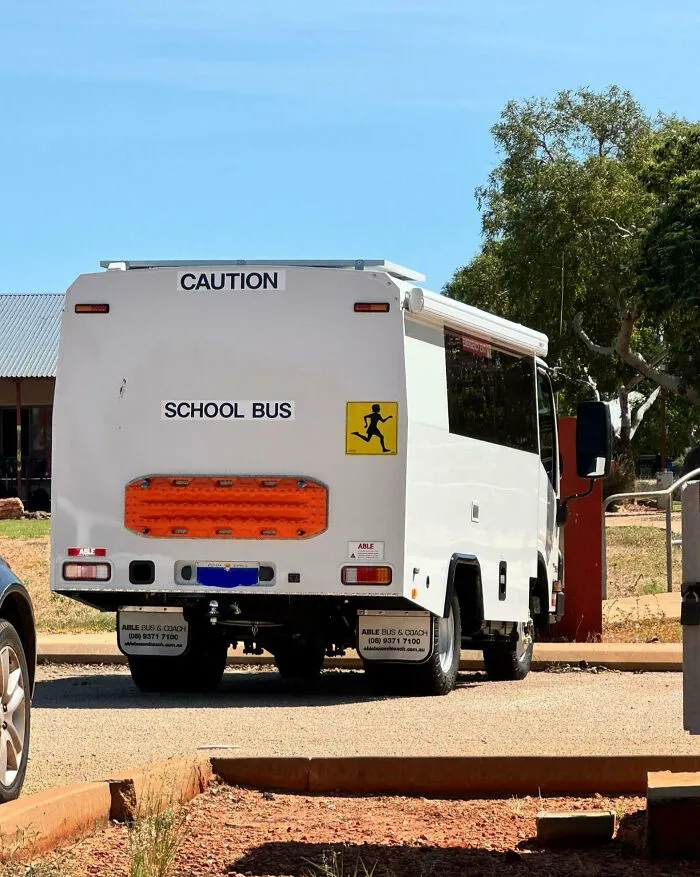 White school bus with caution signs parked outdoors, showcasing impressive things countries implemented for safer transportation.