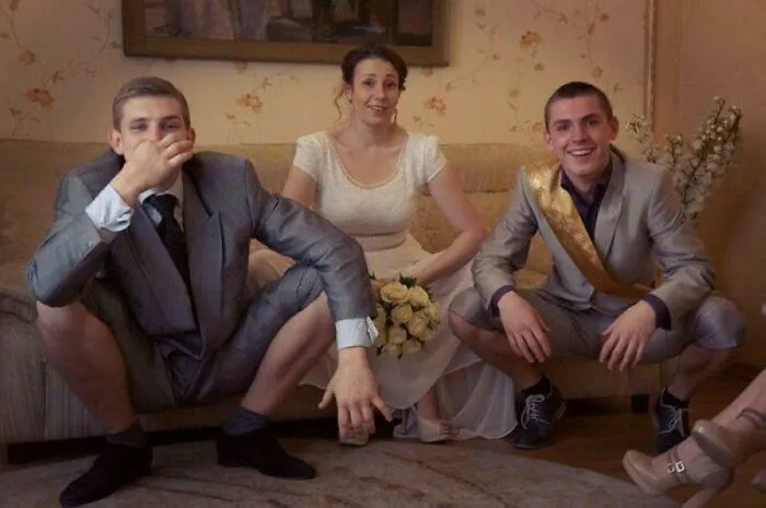 Three people posing awkwardly at a wedding, including a bride and two men in suits, captured in an awkward wedding photo.