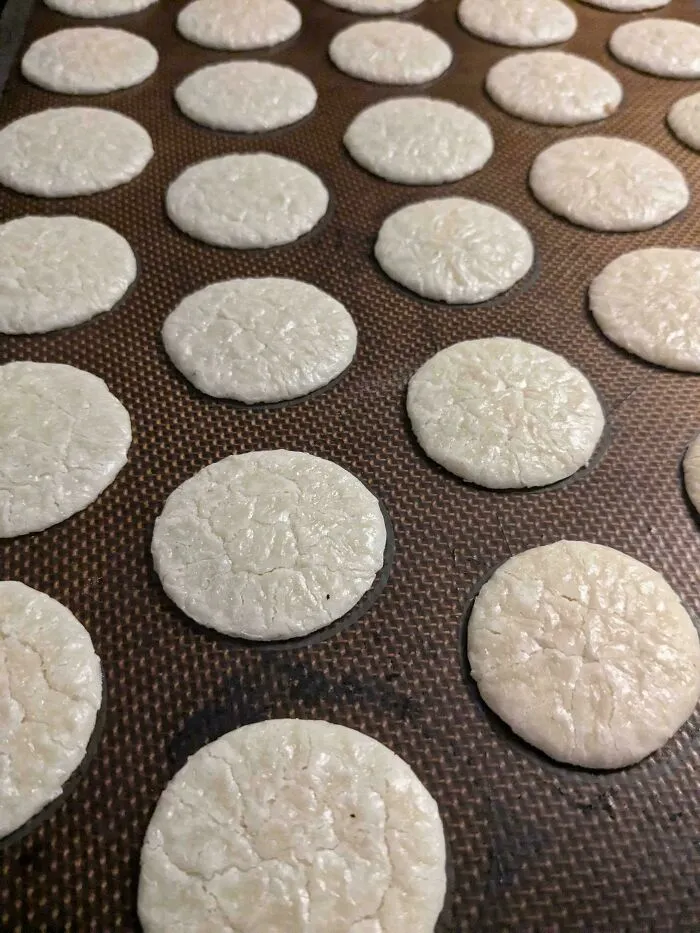 Flat, cracked dessert cookies arranged in rows on a baking tray showcasing ways people managed to ruin dessert.