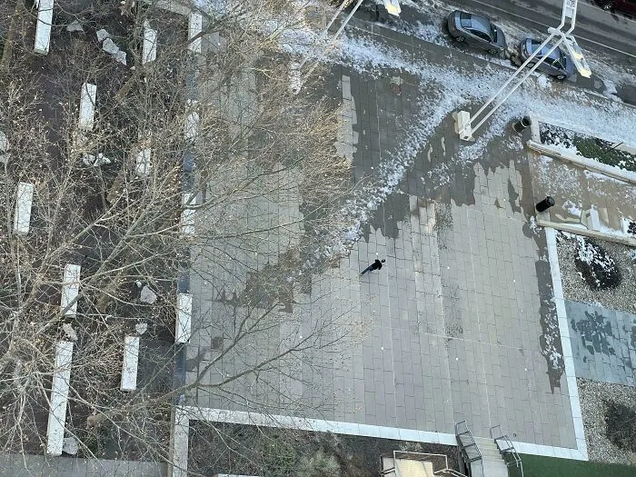 Aerial view of a city plaza showing desire paths worn through snow where pedestrians walk off the planned sidewalks.