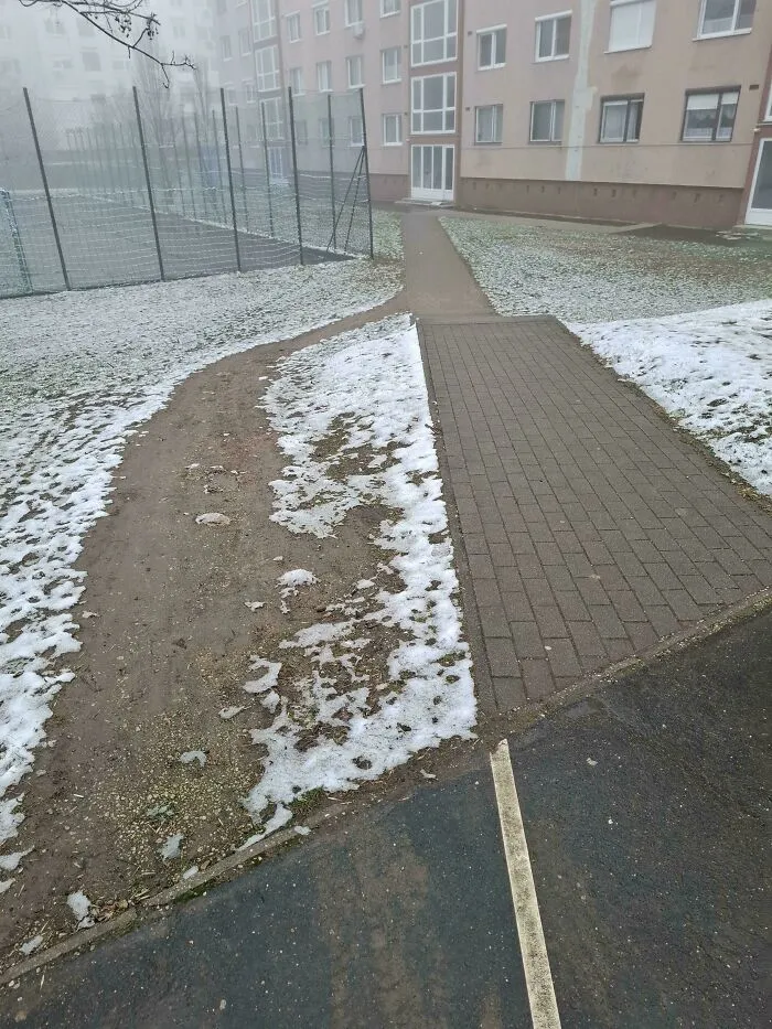 Footpath and desire path in snowy urban area showing how people walk versus city planning in reality.