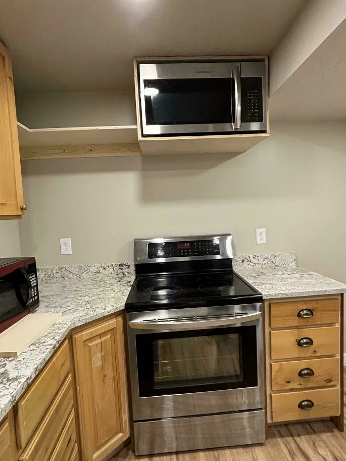 Cocina con diseño defectuoso que muestra un microondas colocado sobre la estufa, error de diseñadores e ingenieros.