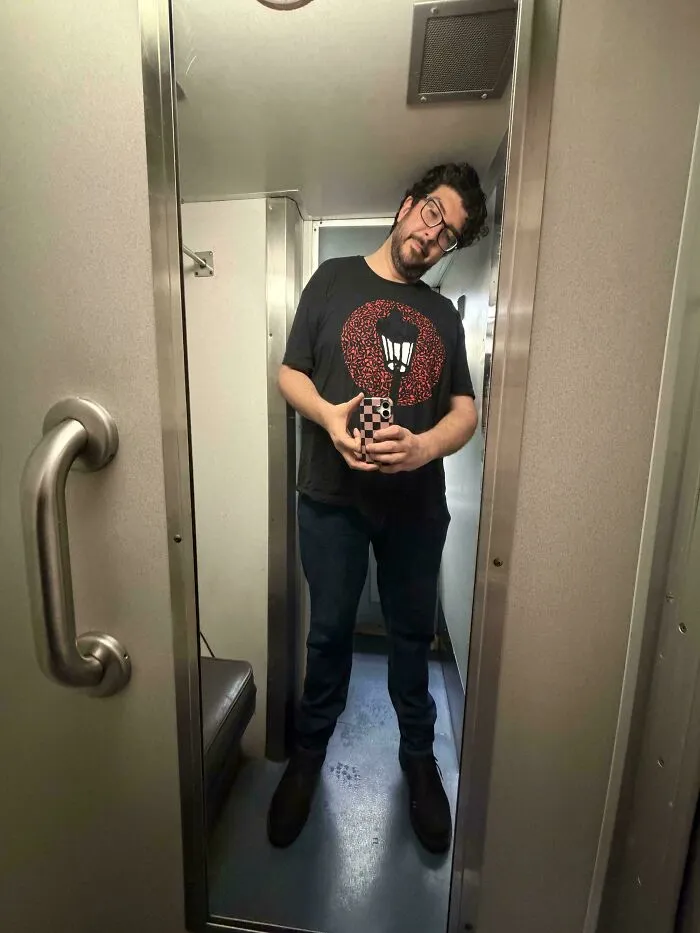 Tall person taking a selfie inside a narrow room, illustrating common struggles only tall people face in small spaces.