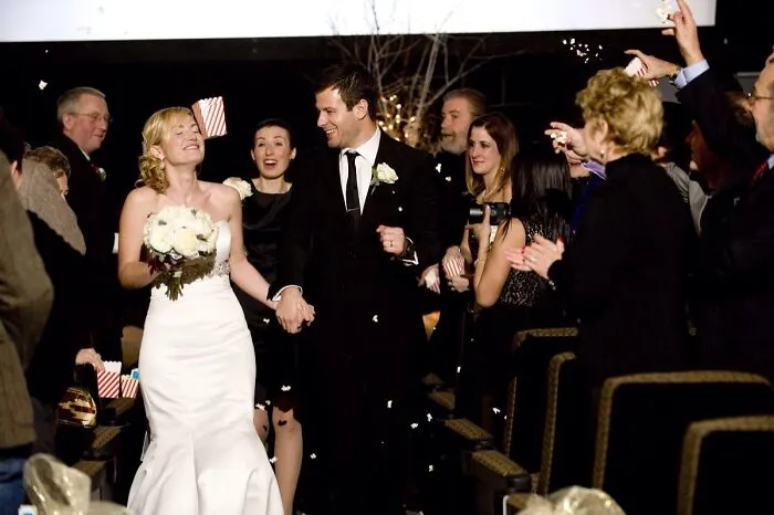 Bride and groom walking down the aisle smiling as guests throw confetti in this awkward wedding photo moment.