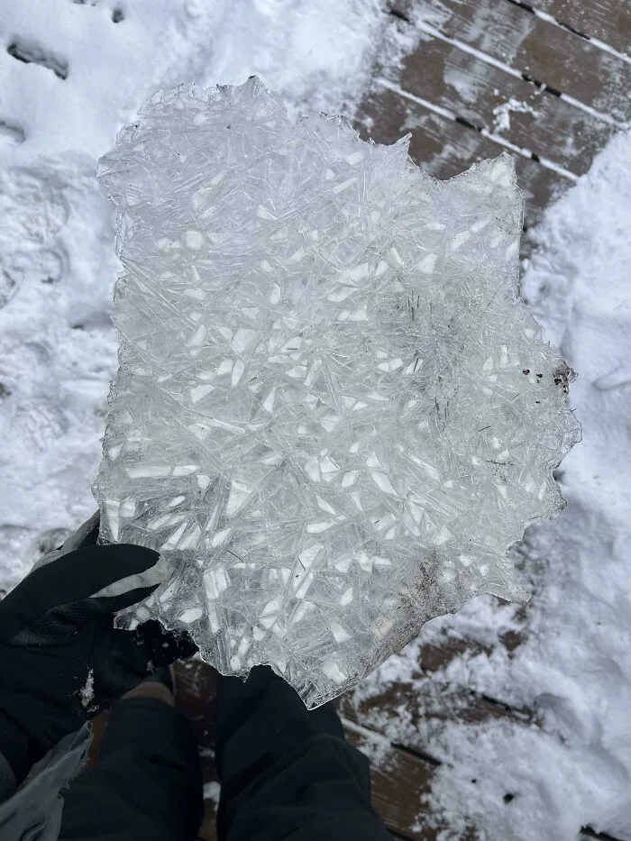Person holding a large piece of cracked ice outdoors in snowy winter, showcasing cozy winter images without stepping into the cold.