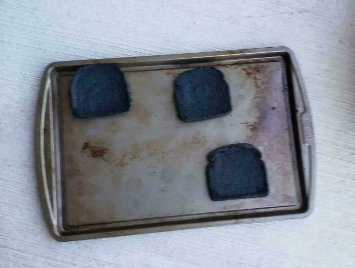 Bandeja con tres rebanadas de pan quemado, error tonto en la cocina capturado con toque de humor inesperado.