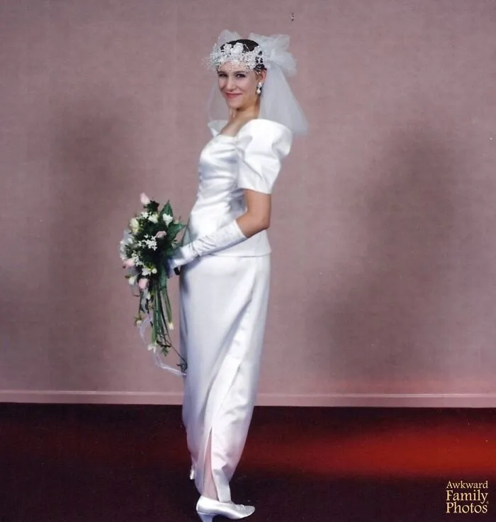 Bride in a vintage wedding dress and gloves posing awkwardly with a bouquet in an awkward wedding photo setting.
