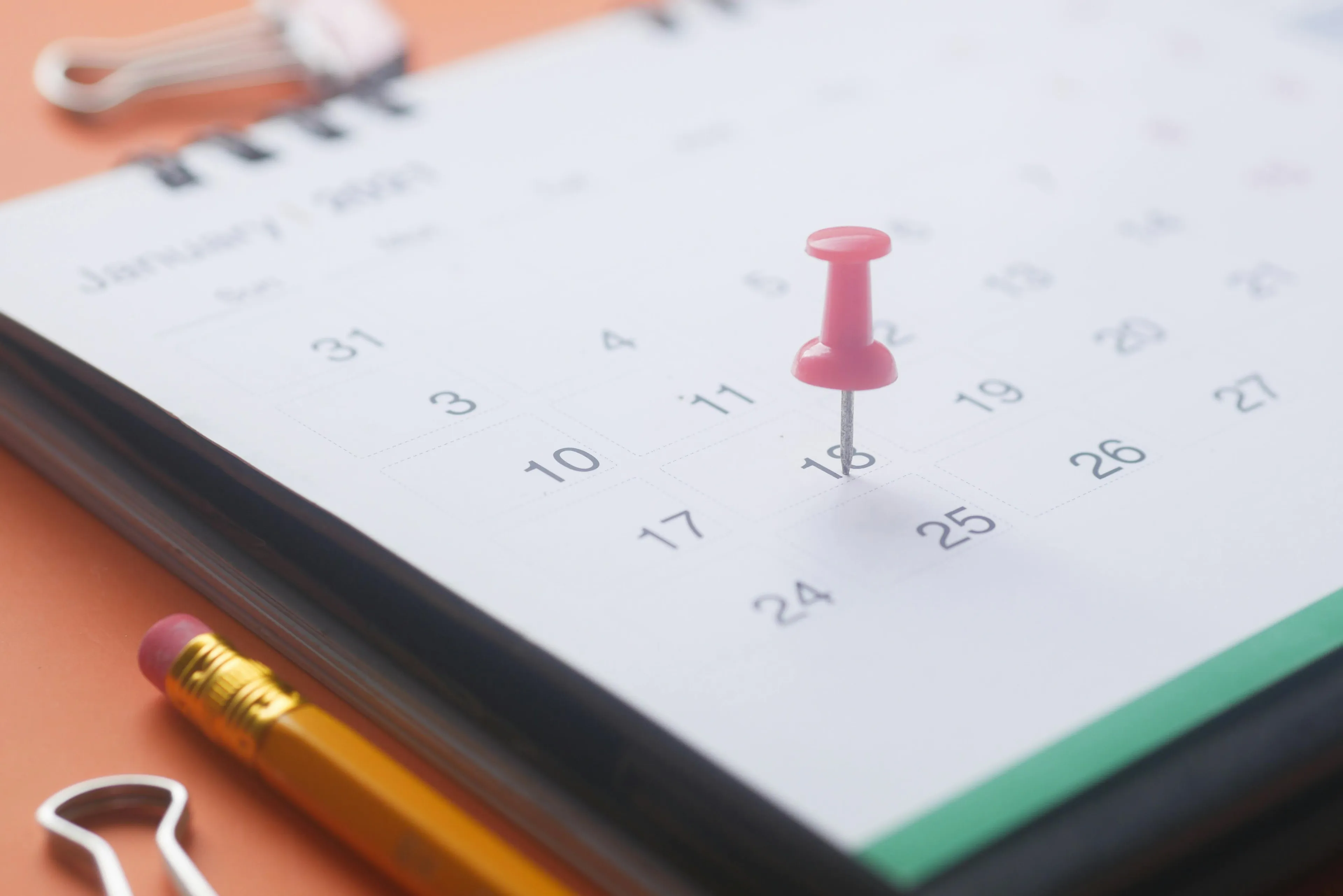 Close-up of a calendar page with a red pushpin marking a date related to deadly decoys and U.S. holidays annually fixed.
