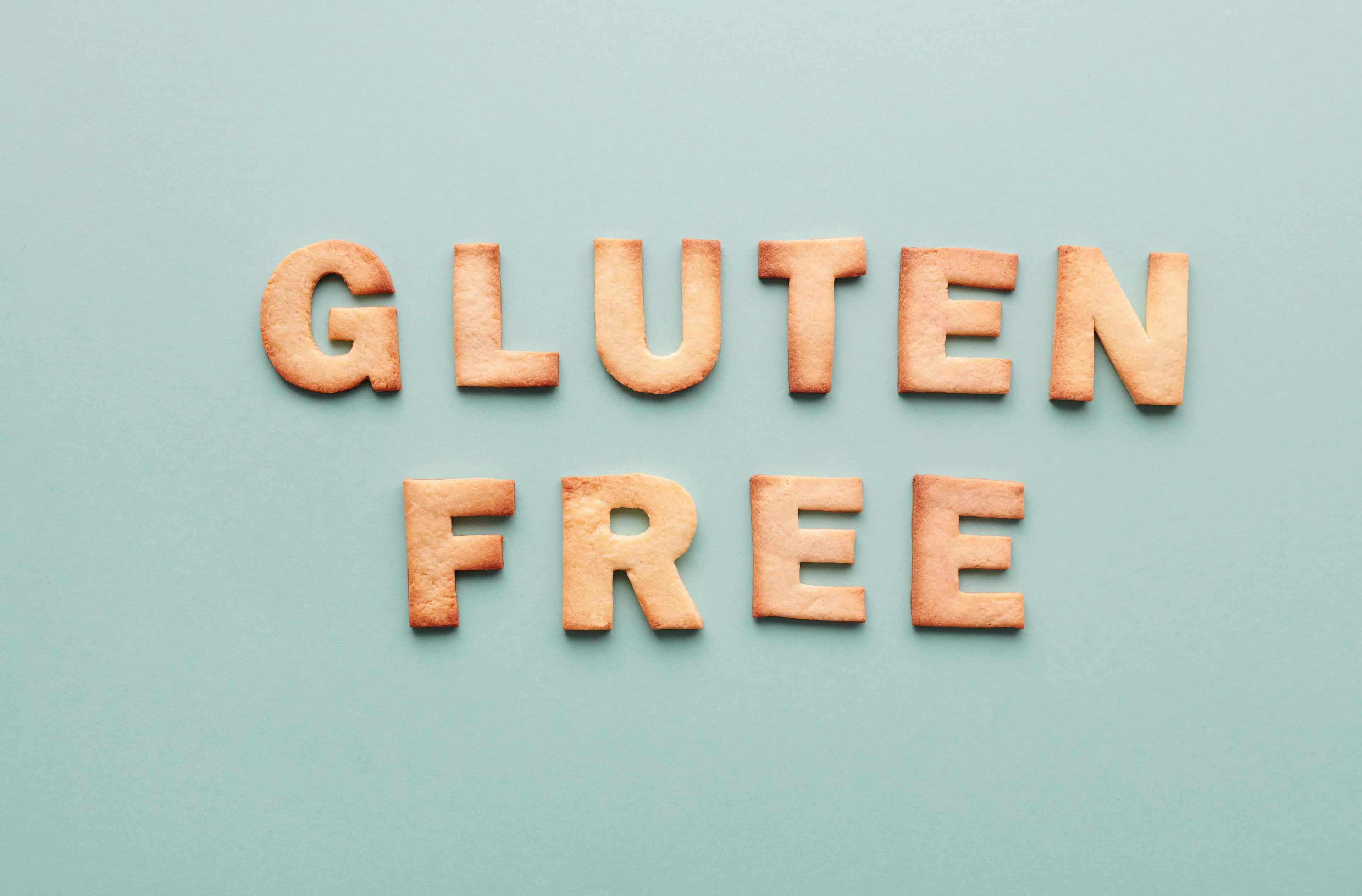 Gluten-free cookie letters spelling out gluten free on a light blue background representing naturally gluten-free foods.