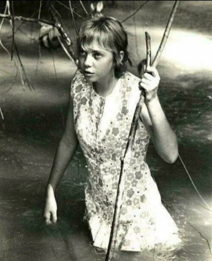 Young woman wading through water holding a stick, representing unsettling history and crime stories.