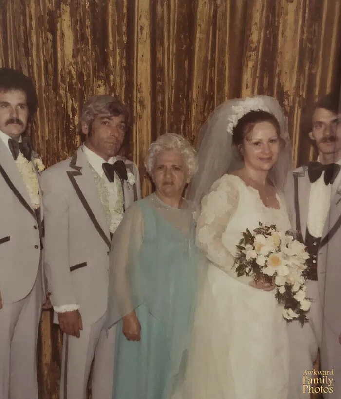 Vintage awkward wedding photo with bride, groom, family members posing with serious and unusual expressions.