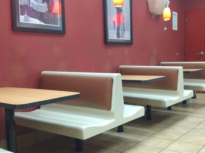 Worn down restaurant booths and tables showing signs of wear on seats and edges in everyday objects.