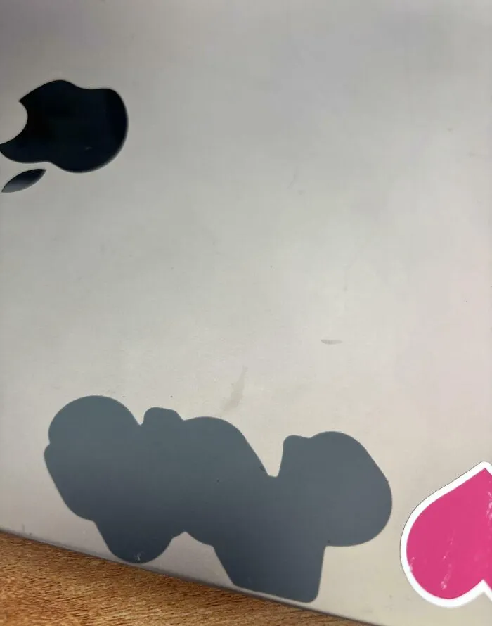 Worn down Apple logo sticker on a laptop showcasing everyday objects deteriorating in unexpected ways.