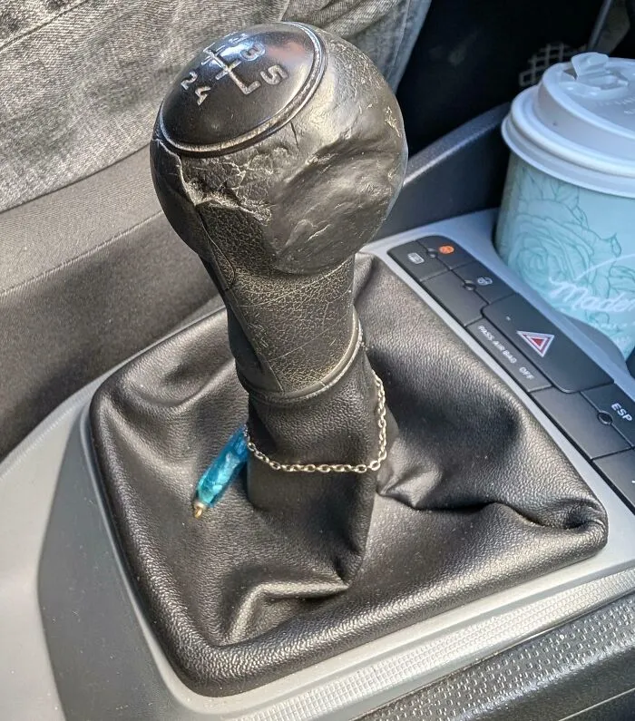 Worn down car gear shift knob showing cracks and smooth areas from everyday use over time.