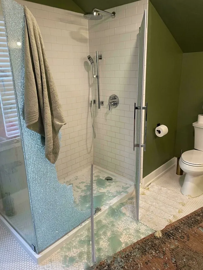 Ducha con puerta de vidrio rota y fragmentos de cristal por el suelo, muestra errores costosos en el hogar.