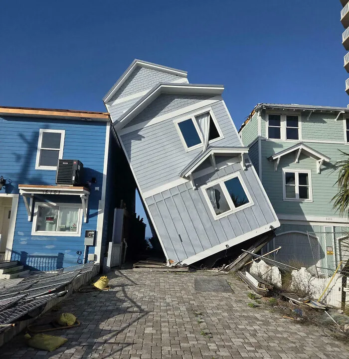 Casa inclinada entre casas normales en un vecindario, mostrando errores costosos que podrían hacerte decir ouch.