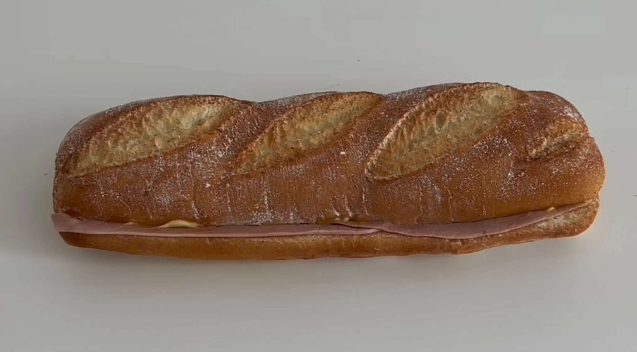 Realistic sandwich or cake illusion with baguette bread and deli meat on a plain white surface.