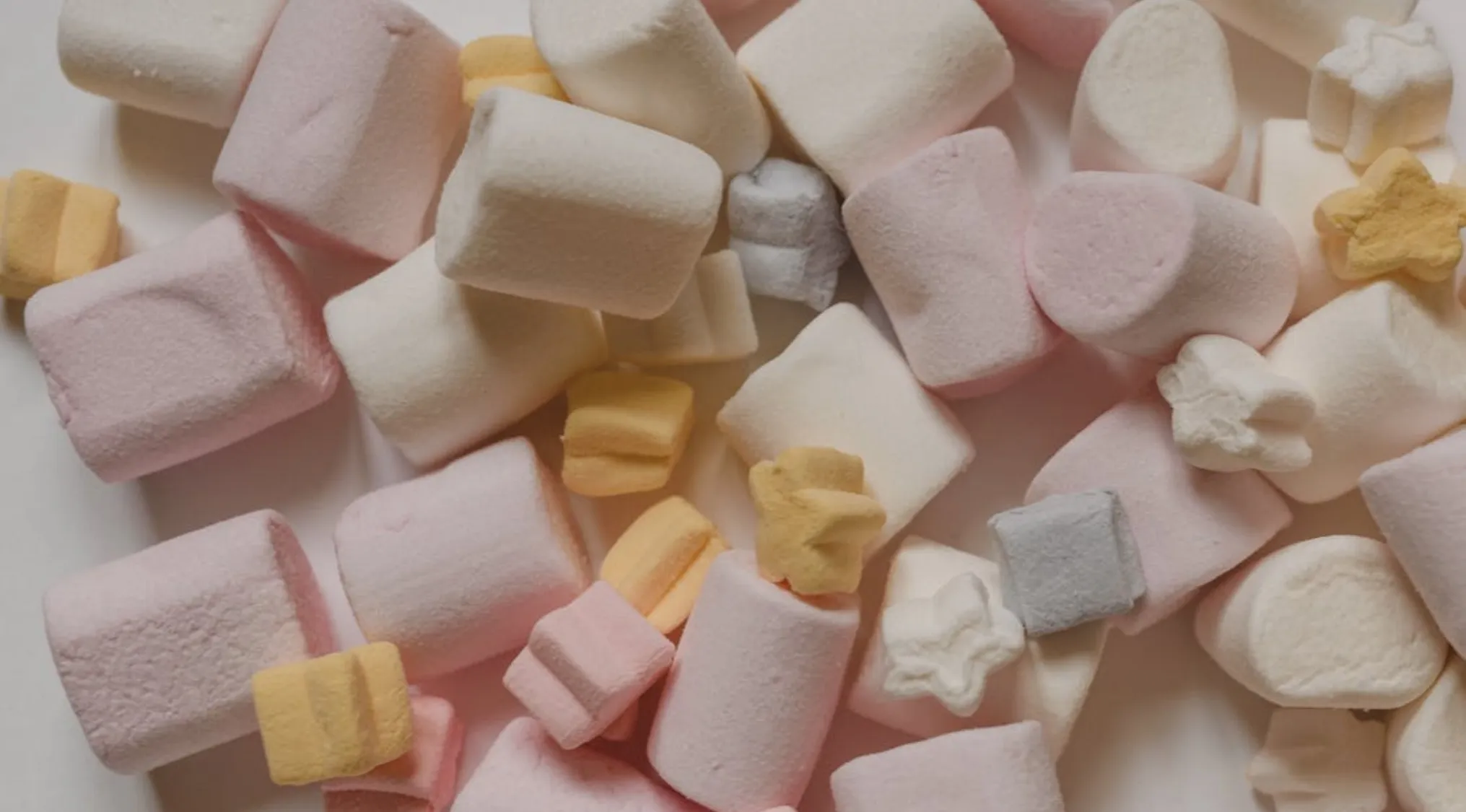 Soft and fluffy marshmallows in pastel colors, showcasing texture and shapes, real or cake concept.