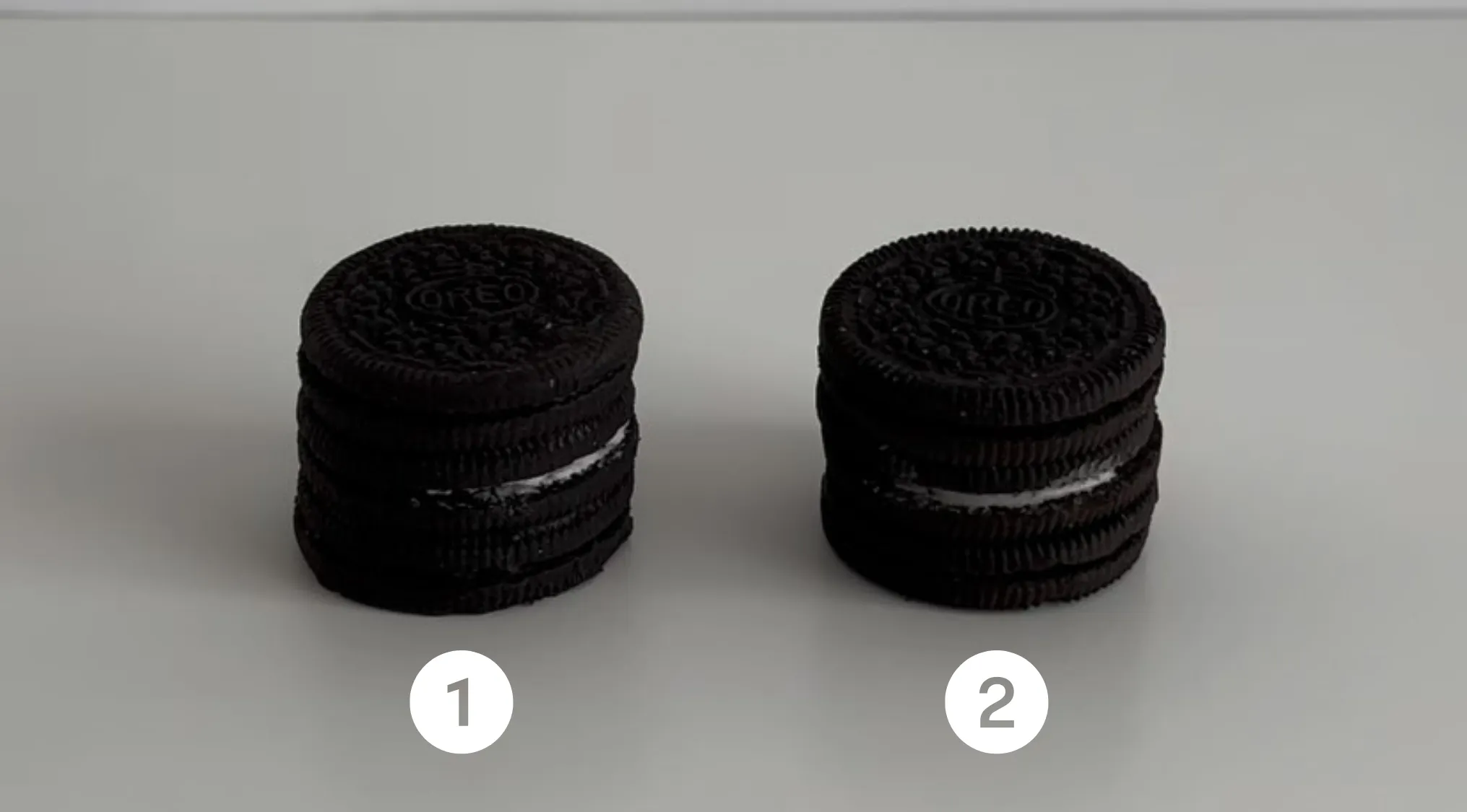 Two stacks of Oreo cookies labeled 1 and 2, challenging viewers to guess which one is real or cake.
